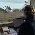 Marie-Laure Voisard écrivant sur son ordinateur face à la mer